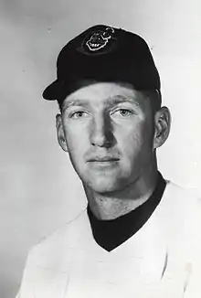 A man in a light baseball jersey and dark cap