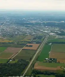 Aerial image of the beginning of a freeway, as it widens from two lanes to four lanes with a grass median. The image shows the rural-urban fringe of Waterloo