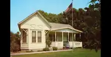 façade of the historical Sproul house in Norwalk. There is a porch on the right and a a flagpole in front flying an American flag.