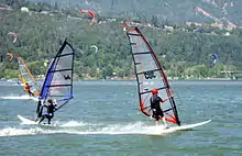 Windsurfers on the river with a forested hillside in the background