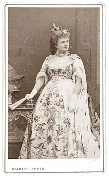  photograph of young white woman standing in ducal robes and coronet, holding a folded fan