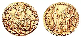 Coin of Huvishka with the divine couple Ommo ("ΟΜΜΟ", Umā) holding a flower, and Oesho ("ΟΗϷΟ", Shiva) with four arms holding attributes. c. 150-180 CE.