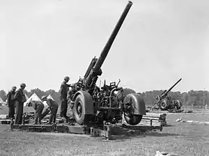 In an open area a large artillery gun points up to the sky