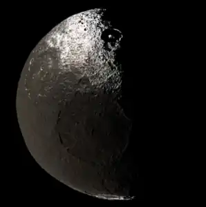 An image of a half-illuminated Iapetus, taken by Cassini  on November 12, 2005 from a distance of  417,000 kilometers (259,000 miles) during its flyby of Saturn. The big crater at the center is Turgis, while the partly-shadowed crater with a central peak to the north is Roland.