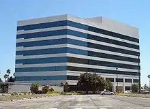 Nondescript eight-story beige building with black windows striped across