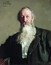 A man with grey hair and a long grey beard, wearing a dark jacket.