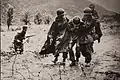 Capt. Emil Kapaun, right, a chaplain with the 3rd Battalion, 8th Cavalry Regiment, helps evacuate an exhausted soldier from the battlefield.