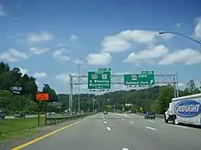 An asphalt highway heading toward some wooded hills.