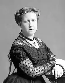 Head and shoulders photograph of a middle-aged Isabel wearing a flower hat