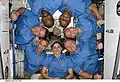 Melvin (upper left), Robert Satcher (upper right) and Nicole Stott form a crew photo circle in Node 2 during STS-129