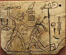 Ivory label depicting the pharaoh Den, found at his tomb in Abydos, c. 3000 BCE. Wepwawet is at the upper right atop a standard.