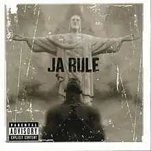 A sepia-colored album cover. On the lower part of the cover, the upper torso of an African American man is seen. His head is turned upward, eyes closed and hands clasped together. On the upper part of the cover, behind the man, stands a white statue of Jesus Christ, with its arms stretched outward, with its palms facing upward. In the center, it reads "Ja Rule" in all capital letters.