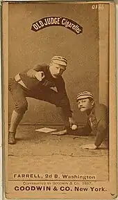 A picture depicting a baseball player who is holding a ball that tagging out another baseball player who attempting to reach base