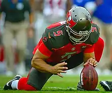 Kneeling to hold a football for the kicker