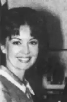 A smiling young white woman with dark hair cut in a fringe