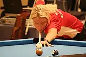 Woman shooting pool while hunched over a table