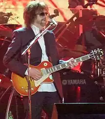 A man standing while playing a guitar and singing into a microphone