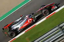 A slanted angle of a silver and red Formula One car at speed on a racing track