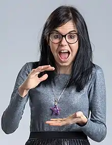 A woman wearing a white sweatshirt, glasses and smiling.