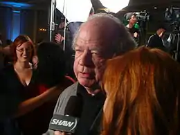 Exhausted-looking older man being interviewed