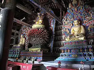 Ming dynasty statues of Vairocana (center), flanked on the far left by Amitabha and on the right by Bhaisajyaguru. Projecting tongues from Vairocana's throne are petals that symbolize his radiance in infinite directions.