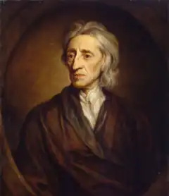 Three-quarter length portrait of a man with a shock of neck-length white hair wearing a loose brown robe and white shirt.