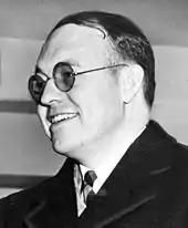 Smiling man in round-rimmed glasses