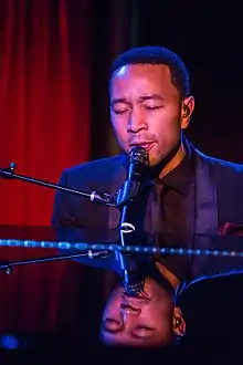 A picture of an African-American man in a suit playing the piano.