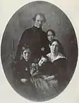 A black-and-white photograph of a mother and father posed with their their son and two daughters