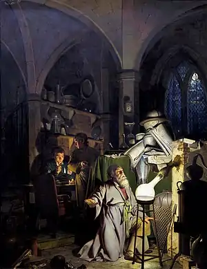 a man kneels in one corner of a darkened room, before a glowing flask; some assistants are further behind him and discernible in the dark