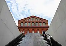 People riding up escalators with a building in the background