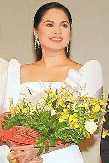 A woman wearing a Philippine terno dress and holding a bouquet