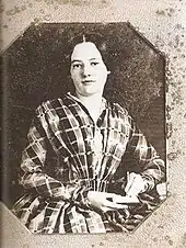 A young white woman with dark hair looks straight ahead.