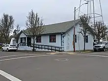 A single-level blue building with a triangular roof and a handicapped ramp. The word "library" pained on the side vertically.