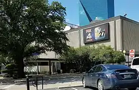 A midcentury low-rise building with a sign bearing Fox 4 and My 27 logos.