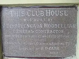 Grey plaque describing construction of the club house