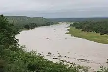 Photograph of a winding river bounded on each side by hills and greenery.