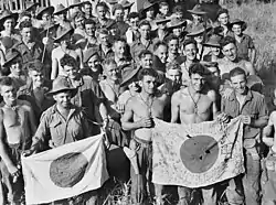 Men wearing military uniforms including jungle greens and slouch hats, display Japanese flags