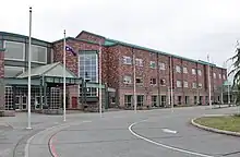 A three-story brick building with a driveway and several flagpoles