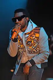 Kanye West wearing sunglasses raps into a microphone