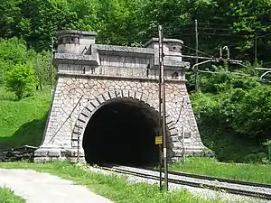 A colour photograph of a railway line running into a tunnel faced with masonry