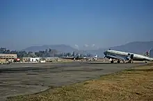 A plane on the tarmac of an airport with a mountainous horizon