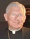 gray-haired man with glasses wearing clerical shirt and collar