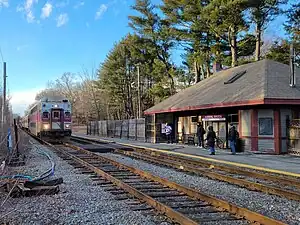 A train arriving at a small wooden railway station in a rural area