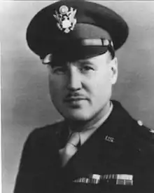 Head and shoulders of man in uniform with peaked cap and thin mustache.