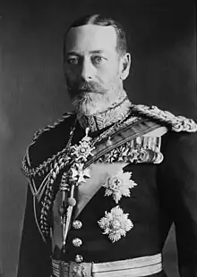 George V is pale-eyed, grey-bearded, of slim build and wearing a uniform and medals.