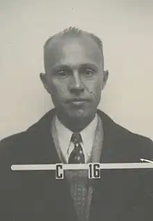 Head and shoulders mug shot of middle-aged man in suit and tie. Lettering reads "C 16"