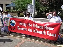 Klamath tribes members holding a banner that reads: Bring the Salmon Home / Remove the Klamath Dams