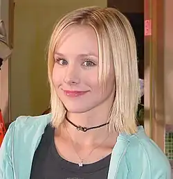 Head and shoulders shot of wide-eyed, young blond woman smiling into the camera.