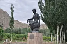 Statue of monk sitting with the right leg touching his left knee